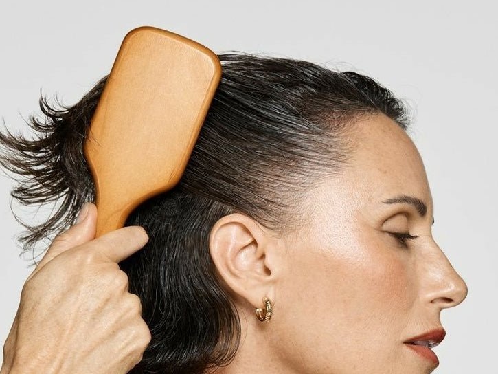 Photo of a woman brushing her short, black hair