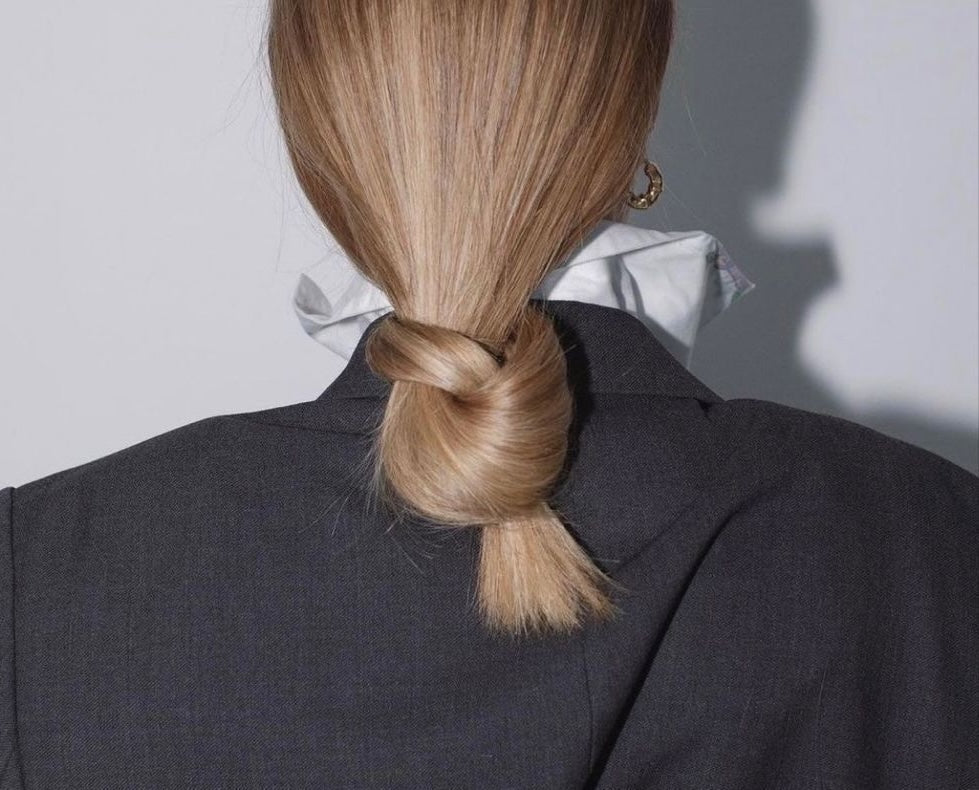 Image of a woman with her long, blonde hair in a low, loose bun