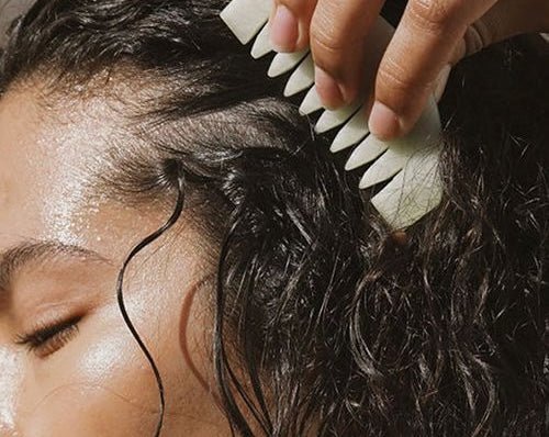 Image of a woman combing her curly, black hair