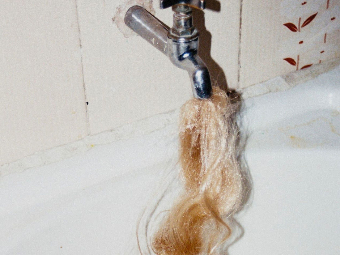Photo of a faucet with long, blonde hair coming out of the spout