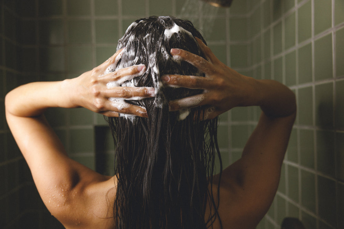 Image showing a woman in the shower applying the Anti-Dandruff shampoo on her hair and scalp