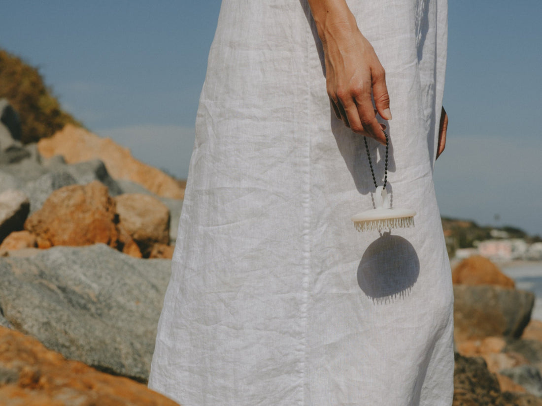 Photo of a woman in a white dress holding the white Scalp Brush
