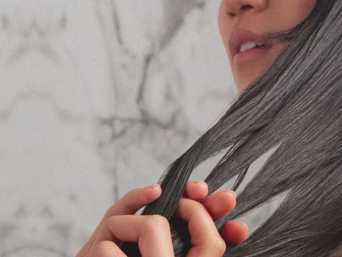 Image of a woman combing her long, dark hair with her fingers