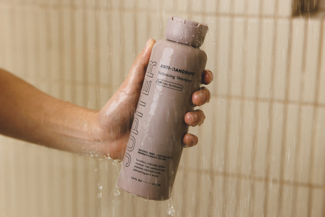 Photo of the Anti-Dandruff Balancing Shampoo held by a hand in the shower