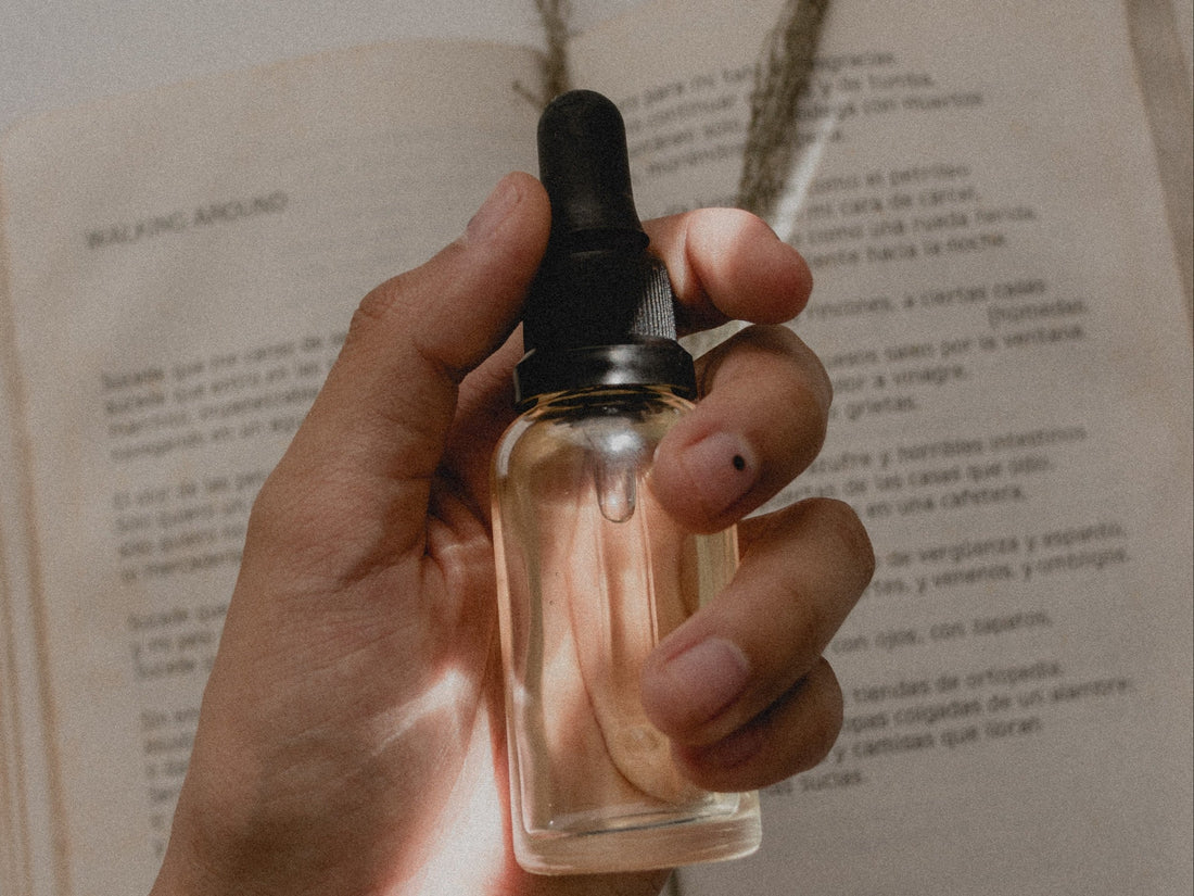 Image of a hand holding a bottle of oil with an open book in the background