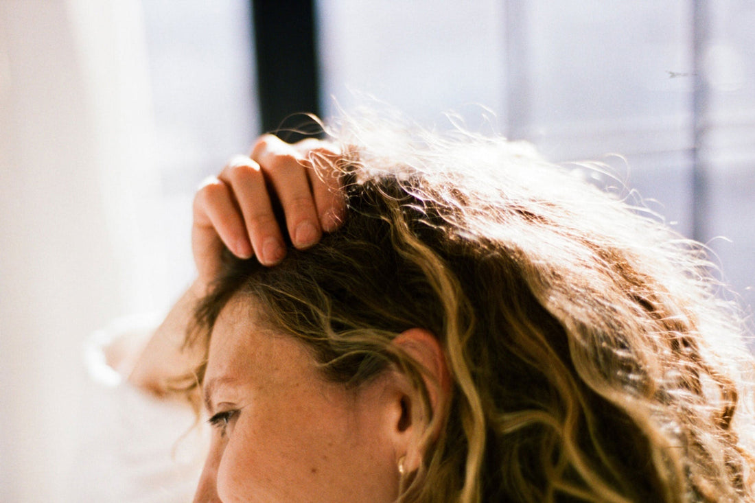 Photo of a woman with curly hair scratching her scalp
