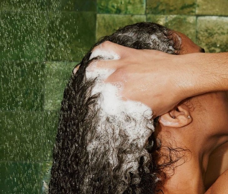 Image of a woman shampooing her curly, black hair