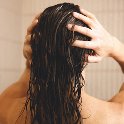 Image showing a woman in the shower applying the Anti-Dandruff shampoo on her hair and scalp