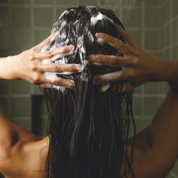 Image of a woman in the shower applying the Daily Hydration shampoo